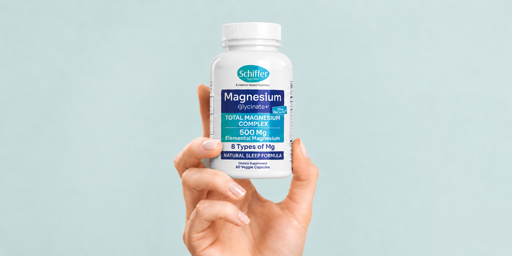 Hand holding a bottle of Schiffer Magnesium supplement against a light blue background